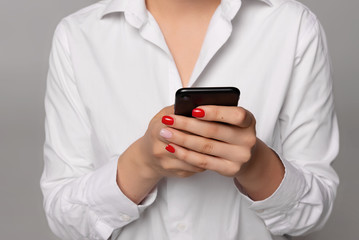 cropped view of businesswoman in white shirt using smartphone isolated on grey 