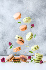 Flying French macaroons and flowers on grey background. Food levitation concept.