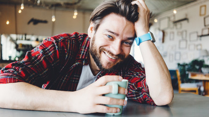 Portrait of handsome young smiling man. Sitting in art design bright interior