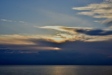 Naklejka na ściany i meble A sunset in the clouds above the sea 