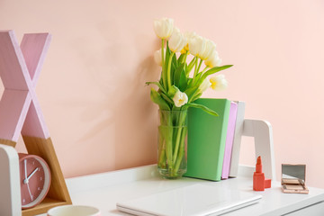 Modern stylish workplace with flowers near color wall