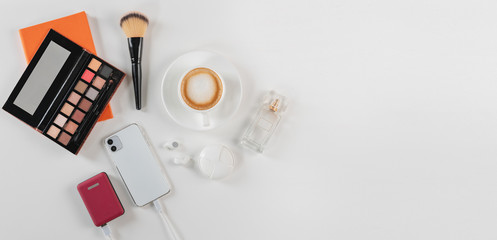 Feminine desk wokrspace with cosmetics, perfumes, coffee and smartphone power bank. Flat lay, copy space. Female office morning concept