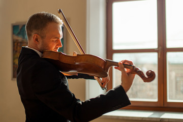 young talented professional man gracefully play violin, handsome musician in formal elegant suit perform classic music © alfa27