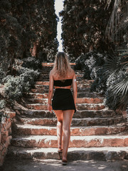 blonde young woman climbing a stairs in the middle of nature on a sunny summer day with little clothes