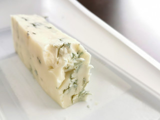 Blue cheese on a white plastic container with copy space on the right side. Selective focus.
