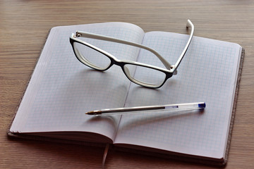 Fototapeta premium glasses and a pen on a notebook for writing