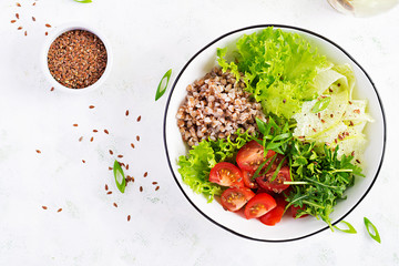Healthy food. Buckwheat salad with cherry tomatoes, daikon, red onion and fresh herbs. Vegan food. Diet menu.  Top view, copy space, flat lay