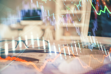 Financial chart hologram with glasses on the table background. Concept of business. Double exposure.