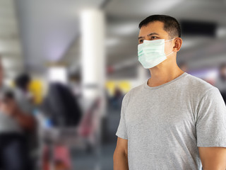 Asian man wearing hygienic face mask on blurred departure hall at airport