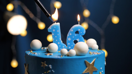 Birthday cake number 16 stars sky and moon concept, blue candle is fire by lighter. Copy space on...