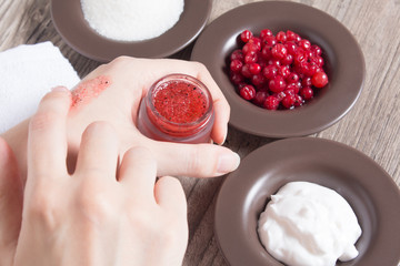 A woman puts her finger on a natural home scrub. Skin care. Natural ingredients for making a scrub, sugar, cream, berries. Moisturizing, exfoliating, peeling. Home Cosmetics, Spa Treatment, eco, vegan