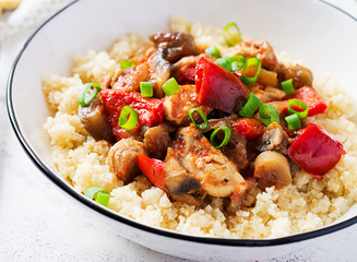 Bulgur and sauteed chicken, mushrooms, eggplants, paprika and tomatoes in a white bowl.