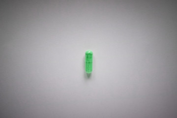 one green pill on a plain background