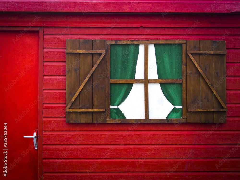 Canvas Prints Closeup shot of a painted wooden window on a red wall with a red door next to it