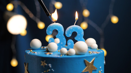 Birthday cake number 33 stars sky and moon concept, blue candle is fire by lighter. Copy space on...