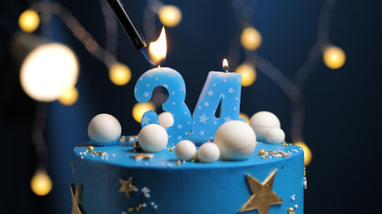 Birthday cake number 34 stars sky and moon concept, blue candle is fire by lighter. Copy space on...