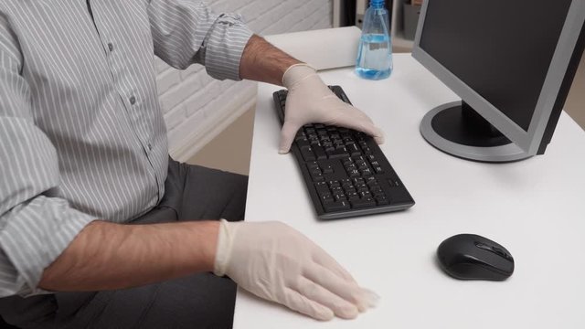 concept of cleaning or disinfecting the office - a businessman cleans the workplace, computer, desk, uses a spray gun and paper napkins. Cleaning surfaces from microbes, viruses and dirt.
