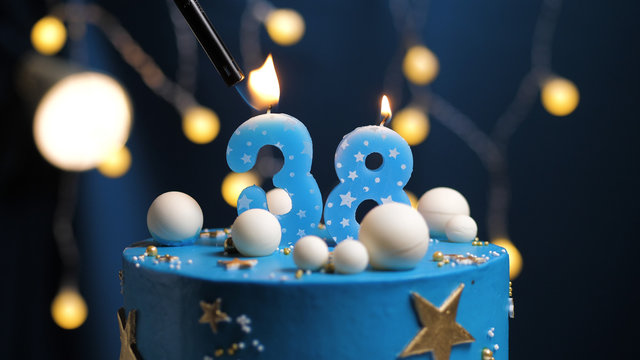 Birthday cake number 38 stars sky and moon concept, blue candle is fire by lighter. Copy space on right side of screen. Close-up