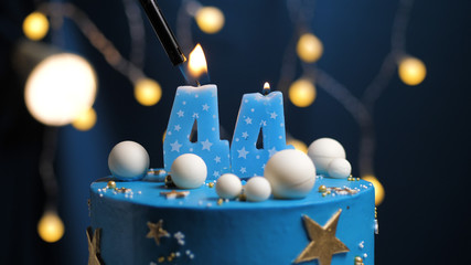 Birthday cake number 44 stars sky and moon concept, blue candle is fire by lighter. Copy space on...