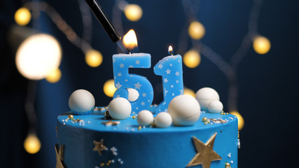 Birthday cake number 51 stars sky and moon concept, blue candle is fire by lighter. Copy space on right side of screen. Close-up