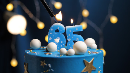 Birthday cake number 65 stars sky and moon concept, blue candle is fire by lighter. Copy space on...