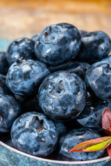 Fresh ripe blueberries in bowl on wooden background