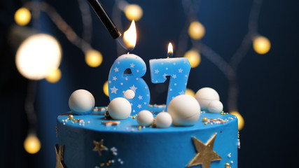 Birthday cake number 67 stars sky and moon concept, blue candle is fire by lighter. Copy space on...