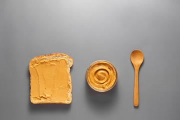 Top view of peanut butter and peanut toast over grey background.