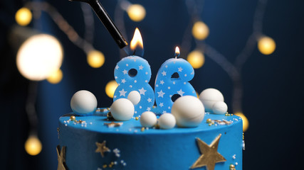 Birthday cake number 86 stars sky and moon concept, blue candle is fire by lighter. Copy space on right side of screen. Close-up