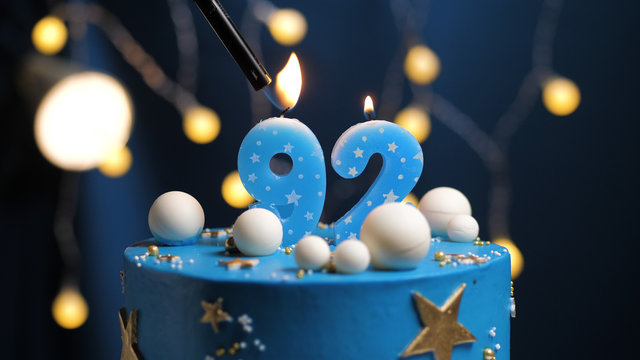 Birthday cake number 92 stars sky and moon concept, blue candle is fire by lighter. Copy space on right side of screen. Close-up