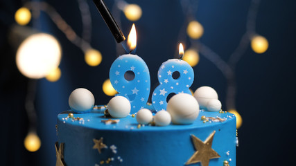 Birthday cake number 98 stars sky and moon concept, blue candle is fire by lighter. Copy space on...