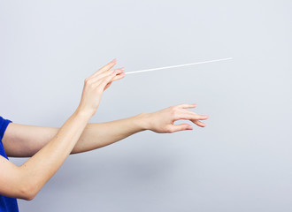 Female hands isolated on gray. Woman conductor. Female hands with a conductors  baton.