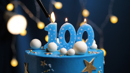 Birthday cake number 100 stars sky and moon concept, blue candle is fire by lighter. Copy space on...