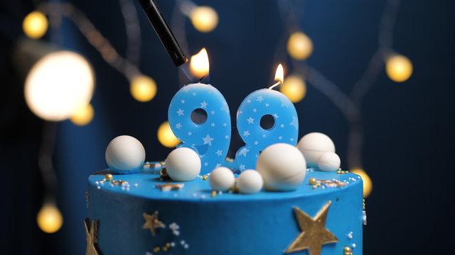 Birthday cake number 99 stars sky and moon concept, blue candle is fire by lighter. Copy space on right side of screen. Close-up