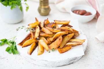 Home-made fried potatoes in slices with herbs and ketchup, selective.