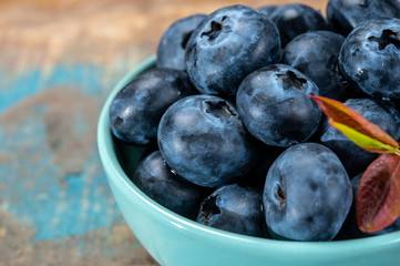 Fresh ripe blueberries in bowl on wooden background