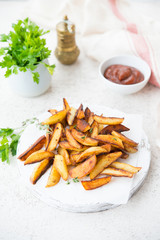 Home-made fried potatoes in slices with herbs and ketchup