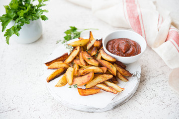 Home-made fried potatoes in slices with herbs and ketchup, rustic potatoes,