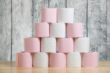 A stack of pink and white toilet paper on a table on a wooden background