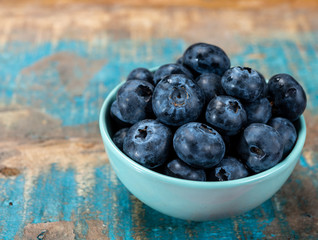 Fresh ripe blueberries in bowl on wooden background