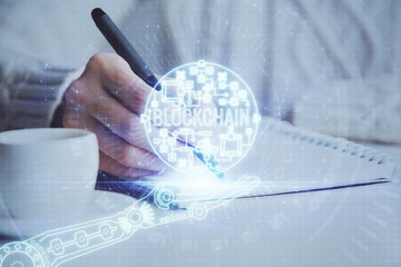 Cryptocurrency hologram over hands taking notes background. Concept of blockchain. Multi exposure
