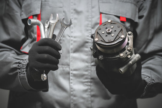 Auto Mechanic Showing A Broken Air Conditioning Compressor Close Up.