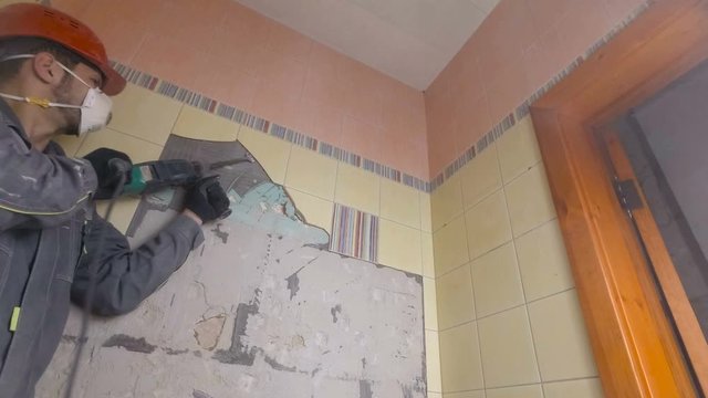 Demolition of old tiles with jackhammer. Renovation of old walls in the bathroom or kitchen