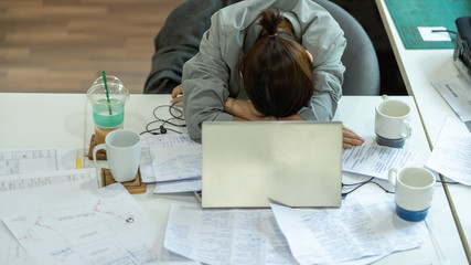 female company employee tired or stressed from working at home until falling asleep on a desk in front of a laptop.