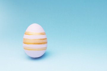Pink Easter egg striped on blue background with a copy space
