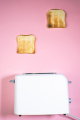 Toaster and bread slices Cooking bread in a toaster on a pink background close up. top view