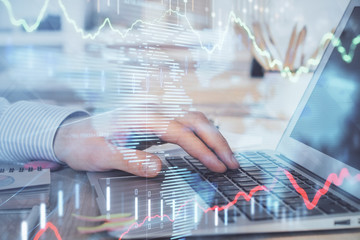Double exposure of stock market graph with man working on laptop on background. Concept of financial analysis.
