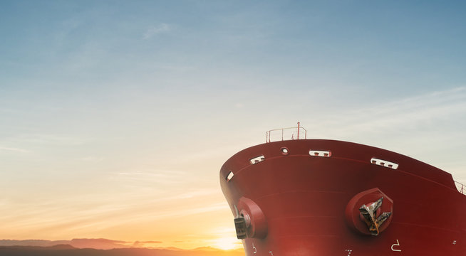 Close up of large red merchant crago ship in the ocean underway. at sunrise or sunset .Performing cargo export and import operations.