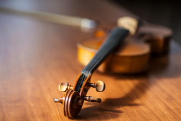 close-up photo of musical instrument violin lying on wooden table. classical music instrument, music concept - obrazy, fototapety, plakaty