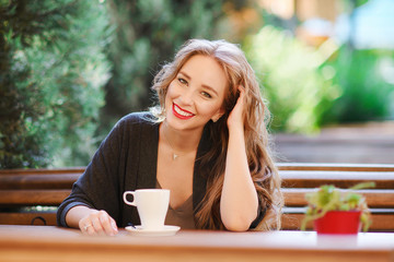 Portrait of a beautiful young long-haired girl in a cafe with a cup of coffee